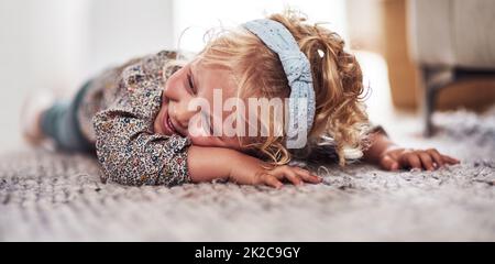 Je vais vous poser ici. Photo courte d'une adorable petite fille qui s'est posée seule sur le sol du salon à la maison. Banque D'Images