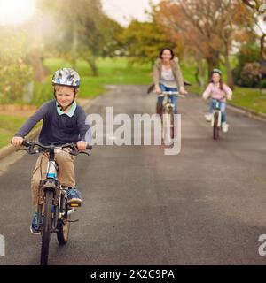 C'est une belle journée pour une balade à vélo. Prise de vue d'une mère et de ses deux jeunes enfants à vélo à l'extérieur. Banque D'Images