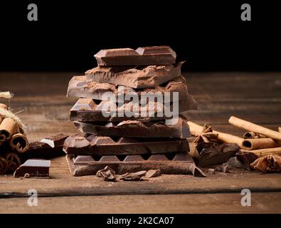 morceaux cassés de chocolat noir, bâtonnets de cannelle et anis étoilé sur une table en bois brun Banque D'Images