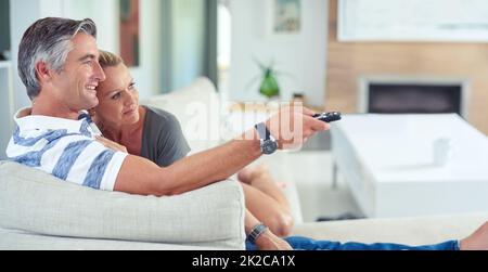 Rafraîchie devant le téléviseur. Photo d'un couple d'âge mûr qui se coud sur le canapé tout en regardant des films à la maison. Banque D'Images