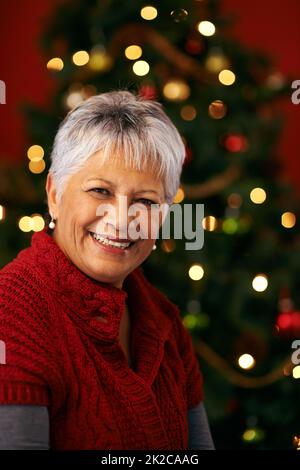 Sourit pour le père noël. Une heureuse femme mûre devant un arbre de Noël Banque D'Images