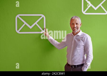 Vérifiez votre boîte de réception. Homme d'affaires mature pointant vers un symbole de message sur fond vert. Banque D'Images