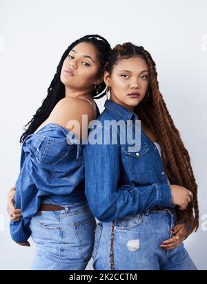 L'air frais et funky. Photo de studio de deux jeunes femmes qui se posent sur un fond gris. Banque D'Images