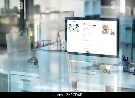 Un autre jour au bureau. Photo d'un ordinateur de bureau sur un bureau dans un bureau moderne tourné à travers le verre. Banque D'Images