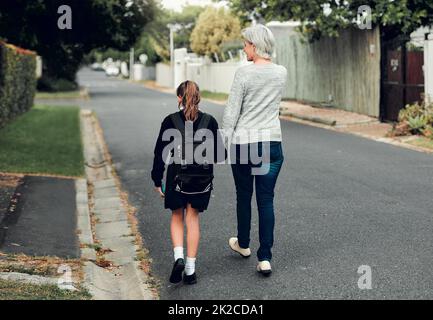 Nous sommes partis apprendre quelque chose de nouveau. Prise de vue en longueur d'une jeune fille d'école marchant avec sa grand-mère à l'école dans les rues de leur quartier. Banque D'Images