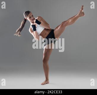 Il a fait un bruit de frappe. Coup de pied d'une jeune femme athlétique pratiquant sa technique de kickboxing. Banque D'Images