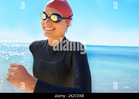 L'entraînement pour sauver des vies. Une jeune femme s'entraîne sur la plage en hiver dans une combinaison et un équipement de natation complets. Banque D'Images