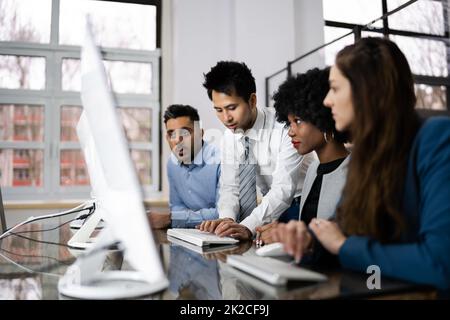 Des gens d'affaires heureux qui utilisent un ordinateur portable discutent sur le lieu de travail Banque D'Images