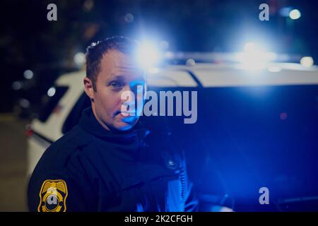 Devinez qui travaille la nuit. Portrait court d'un beau jeune policier en patrouille. Banque D'Images