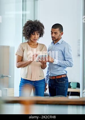 Connexions au bureau. Photo de deux collègues de bureau ayant une discussion sur une tablette numérique. Banque D'Images