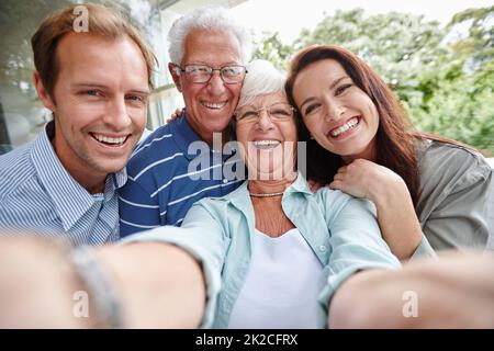 La génération des selfies. Prise de vue courte de quatre adultes prenant un selfie familial. Banque D'Images