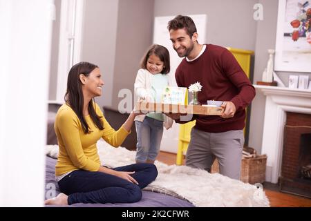 Maman qui se gâta. Un homme et sa fille apportent son petit déjeuner au lit de sa femme le jour de la fête des mères. Banque D'Images