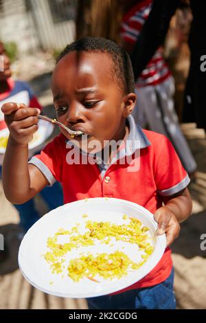 Il n'y aura plus rien sur sa plaque une fois que ça aura été fait. Prise de vue d'enfants nourris à un rayon d'action alimentaire. Banque D'Images