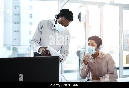 S'engager en toute sécurité pour faire des affaires. Photo de deux agents de centre d'appels travaillant ensemble dans un bureau. Banque D'Images