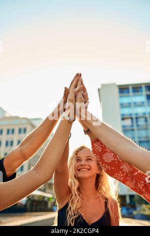 La ville est la nôtre. Photo rognée d'un groupe de jeunes amis en pleine fiving pendant leur séjour dans la ville. Banque D'Images