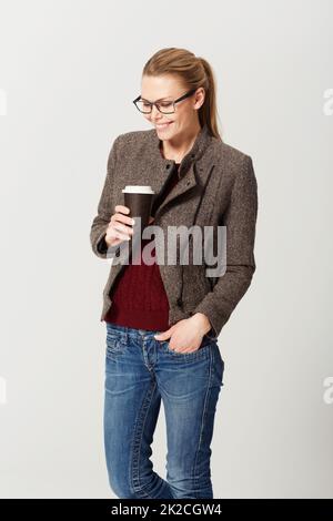 Prendre un café. Petit studio photo d'une jeune femme heureuse et attrayante qui boit un café. Banque D'Images