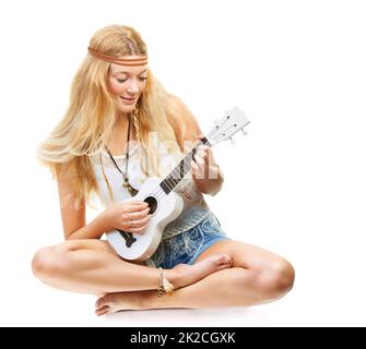 Puis-je jouer mon Ukulele pour vous. Studio photo d'un enfant floral attrayant jouant une guitare isolée sur blanc. Banque D'Images