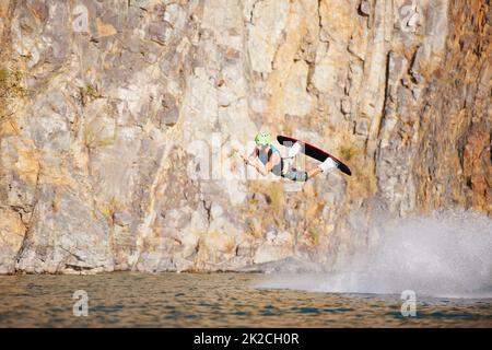 Un jeune homme portant un helmut et un gilet de sauvetage sur un lac. Un jeune homme portant un casque et un gilet de sauvetage sur un lac. Banque D'Images