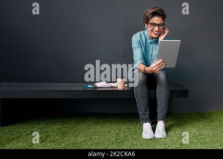 Cela ressemble à un beau spectacle. Prise de vue en longueur d'une jeune femme attrayante assise seule sur un banc à l'extérieur et utilisant une tablette. Banque D'Images