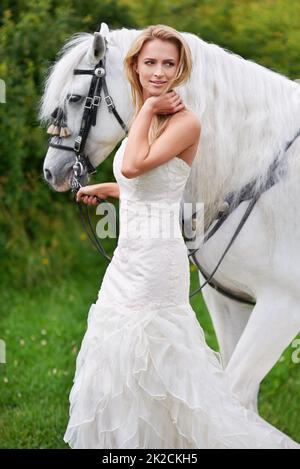 Elle est entrée dans son mariage à cheval. Une jeune mariée attrayante dehors avec son cheval. Banque D'Images