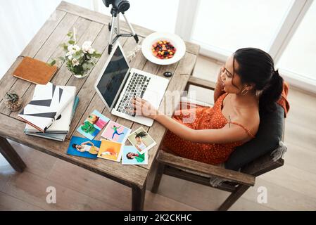 Le multitâche est l'essence même de l'entreprise. Prise de vue en grand angle d'une jeune femme d'affaires attirante assise dans son bureau et utilisant son ordinateur portable pendant un appel. Banque D'Images