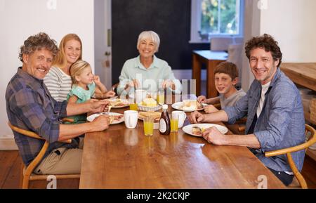 Bonne nourriture et famille - une recette pour le bonheur. Un portrait d'une famille de plusieurs générations heureuse ayant le petit déjeuner ensemble à la maison. Banque D'Images