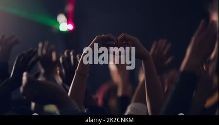 Beaucoup d'amour pour l'année vient de passer. Photo courte d'une jeune femme méconnue qui fait un coeur avec ses mains tout en dansant dans un club. Banque D'Images