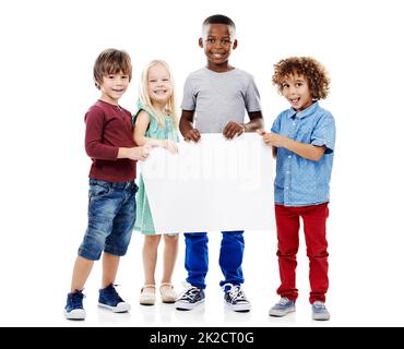 Mes amis ont un message pour vous. Photo en studio d'un groupe de jeunes amis tenant un écriteau vierge sur un fond blanc. Banque D'Images