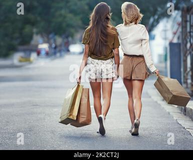 Ils aiment leurs expéditions d'achats. Deux jeunes femmes marchant dans la rue avec des sacs de shopping. Banque D'Images