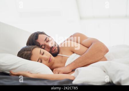 Le vrai amour est d'être heureux même quand vous dormez. Photo d'un jeune couple dormant confortablement dans le lit. Banque D'Images