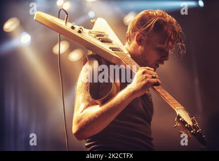 Jeune musicien portant sa guitare hors scène après un concert. Ce concert a été créé dans le seul but de cette séance photo, avec 300 modèles et 3 groupes live. Tous les participants à cette séance photo sont sortis du modèle. Banque D'Images