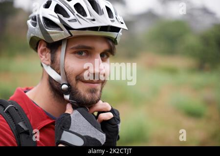 Il est serré. Un jeune cycliste qui attache son casque. Banque D'Images