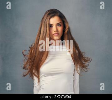 La vraie beauté est propriétaire de qui vous êtes. Portrait studio d'une jeune femme attrayante posant sur un fond gris. Banque D'Images