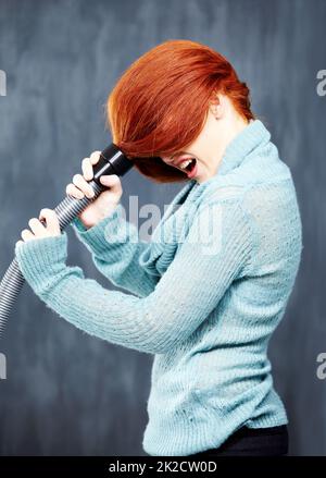 Avoir une mauvaise journée de cheveux. Une jeune tête rouge avec ses cheveux coincés dans l'aspirateur. Banque D'Images