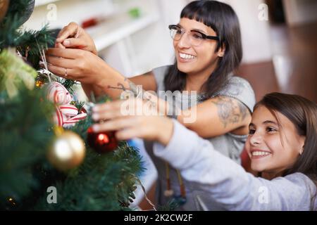 Traditions de Noël préférées. Photo d'une mère et d'une fille qui pendent des décorations de Noël sur un arbre. Banque D'Images