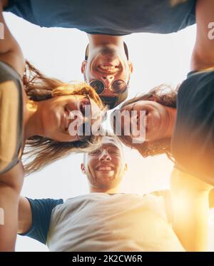 Unis dans l'amitié. Photo sous angle d'un groupe de jeunes amis heureux se posant à l'extérieur. Banque D'Images