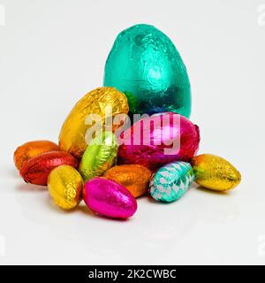 Il vous suffit d'attendre d'être déballé et dévoré. Photo en studio d'un tableau éblouissant d'œufs de pâques multicolores enveloppés de papier d'aluminium. Banque D'Images