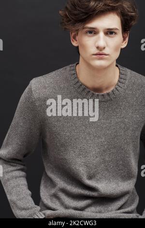 La jeunesse en face mais sage dans les yeux. Portrait d'un jeune homme frais portant des vêtements d'hiver et posant en studio. Banque D'Images