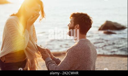C'est un véritable suceur pour le romantisme. Plan court d'un jeune homme proposant à sa petite amie sur la plage. Banque D'Images