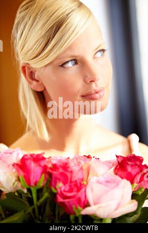 Maintenant, qui les a laissés à la porte. Plan court d'une jeune femme tenant un bouquet de roses roses. Banque D'Images