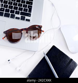 Prêt à prendre la journée. Prise de vue d'un ordinateur portable, de lunettes, d'une souris et d'un ordinateur portable sur une table. Banque D'Images