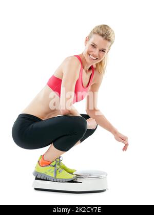 Quand j'ai perdu toutes mes excuses, j'ai obtenu mes résultats. Photo studio d'une jeune femme qui se pèse sur une balance. Banque D'Images