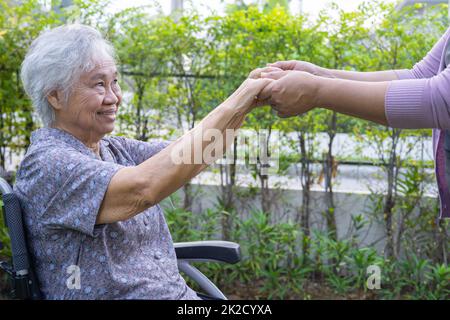 Tenir les mains asiatique senior ou vieille femme âgée patiente avec amour, soin, encourager et empathie au parc. Banque D'Images