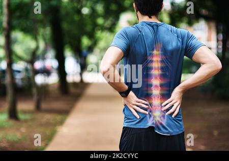 HES l'a surpassé cette fois avec sa formation. Vue arrière d'un jeune homme sportif tenant son dos dans la douleur tout en faisant de l'exercice à l'extérieur. Banque D'Images