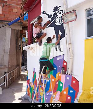 La décoration de leur ville. Photo de deux jeunes artistes du graffiti peignant un dessin sur un mur. Banque D'Images