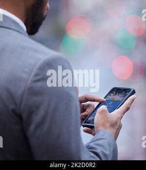 Le site Web de l'entreprise vient bien. Cliché court d'un homme d'affaires méconnu debout seul et utilisant son téléphone portable. Banque D'Images