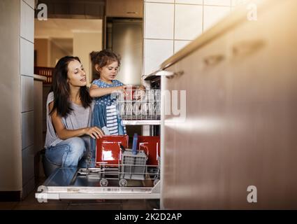 C'est ainsi que nous empilons le lave-vaisselle. Photo d'une petite fille mignonne et de sa mère en train de charger le lave-vaisselle ensemble à la maison. Banque D'Images