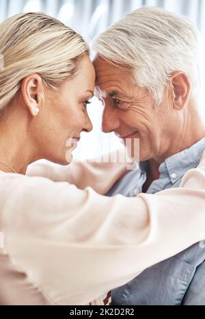 Se perdre dans ses yeux. Photo courte d'un couple affectueux et mature debout face à face dans leur maison. Banque D'Images