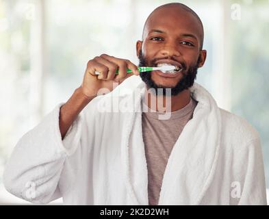 N'oubliez pas de vous brosser les dents deux fois par jour. Photo d'un jeune homme se brossant les dents à la maison. Banque D'Images