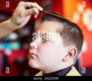 Belle apparence. Gros plan d'un jeune garçon qui obtient une coupe de cheveux dans un salon de coiffure. Banque D'Images